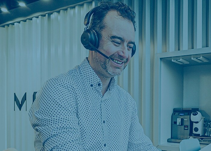 Person working on a laptop in a modern office space while wearing headphones