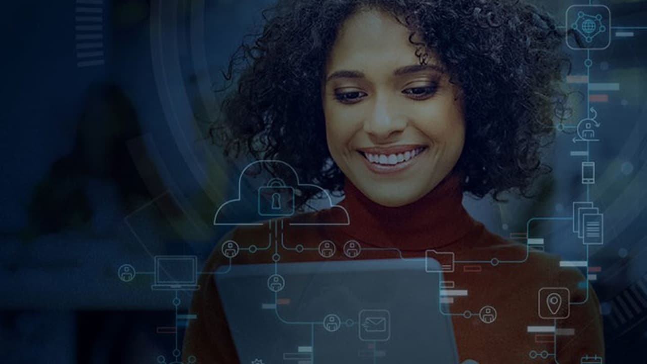 The employee is reviewing electronic gadgets to handle cybersecurity.