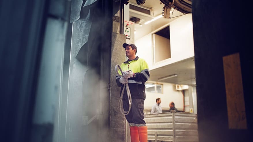 Man with dark hat in yellow vest and orange boots
