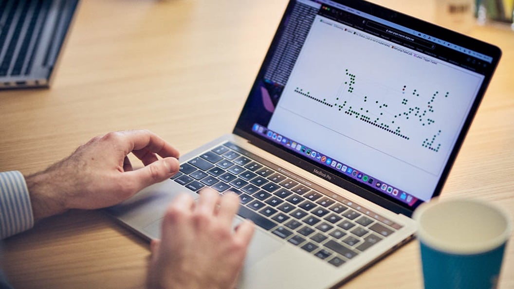 Someone working on a laptop where the screen shows a graphic image with dots.