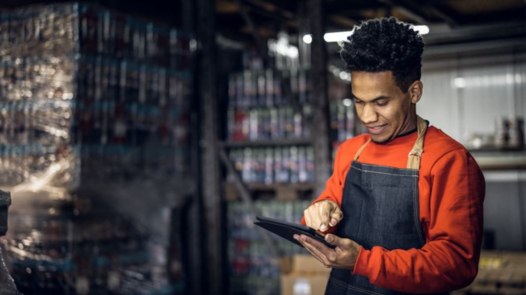 A black man in an orange jumper and denim apron 