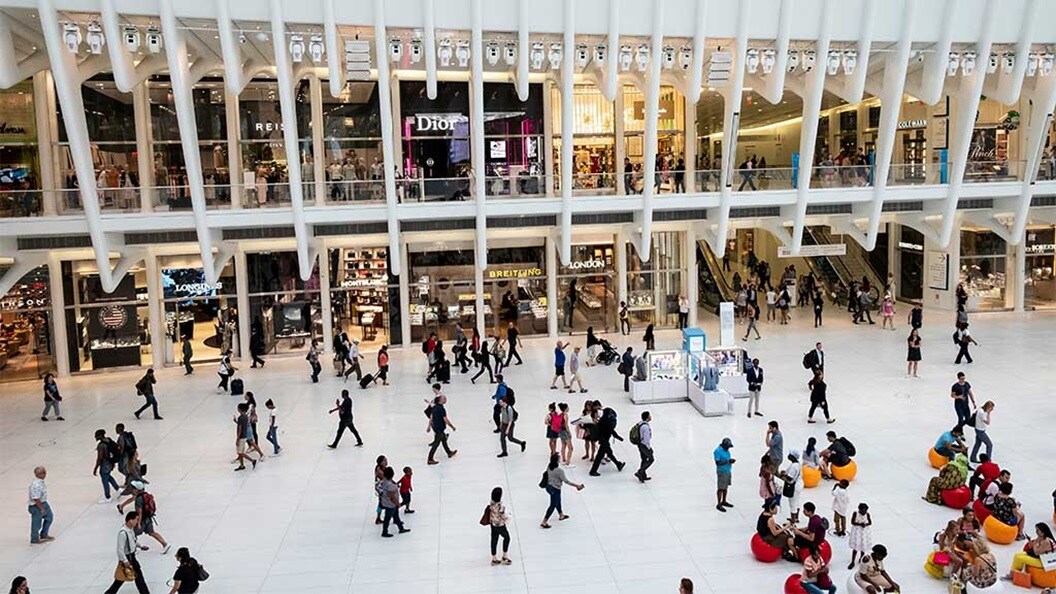 People walking through a spacious shopping mall, browsing stores and enjoying the vibrant atmosphere.
