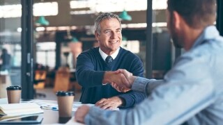 Two male shaking hands at a table