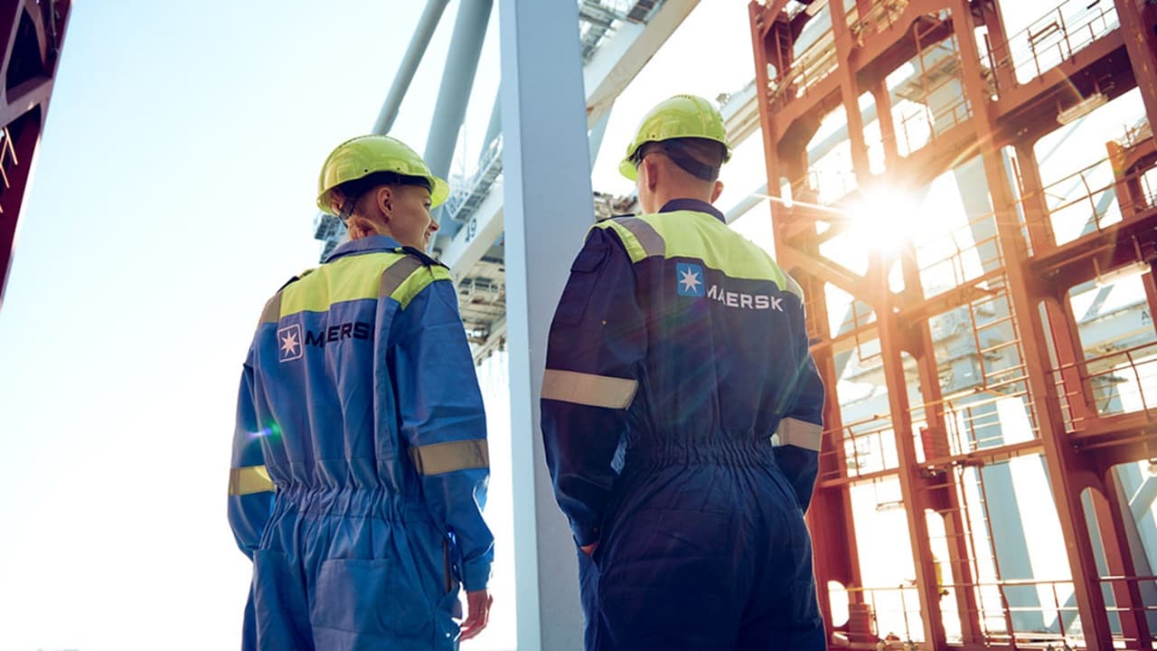 Male and female cadet in Maersk boilersuit look out at port