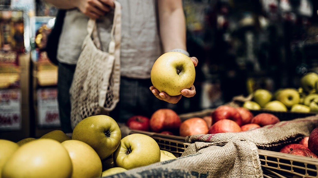 Hand of a woman taking an apple out of a shelf