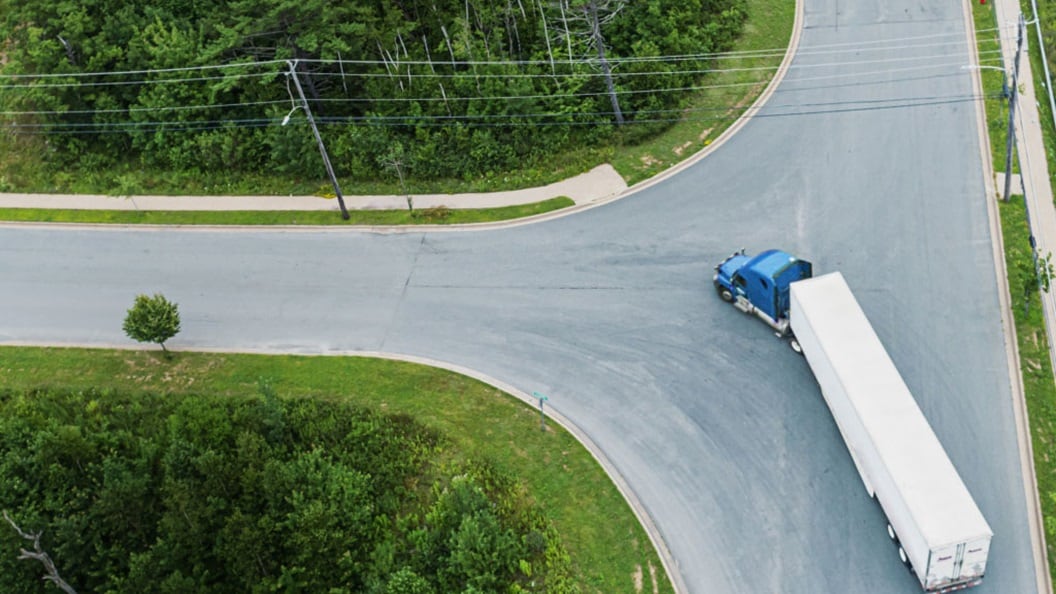 Ariel shot of a truck driving along a curved road. 