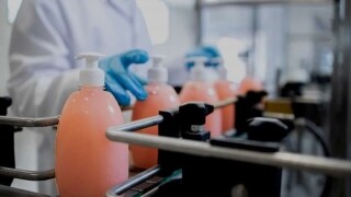 Pump bottles lined up on a conveyor belt in a factory