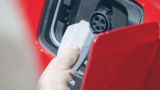 Plugging the charging wire on a red car