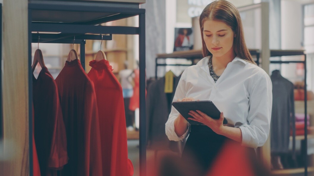 A woman in a retail clothing store looking at data on their tablet