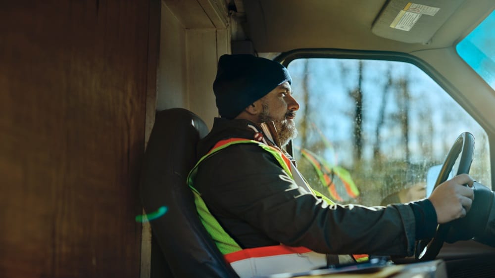 Close-up of a man behind the steering wheel in a truck carrying inland cargo.