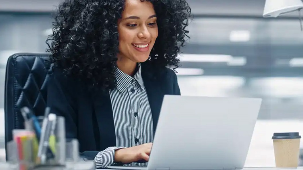 A woman sitting in an office looking at a laptop.