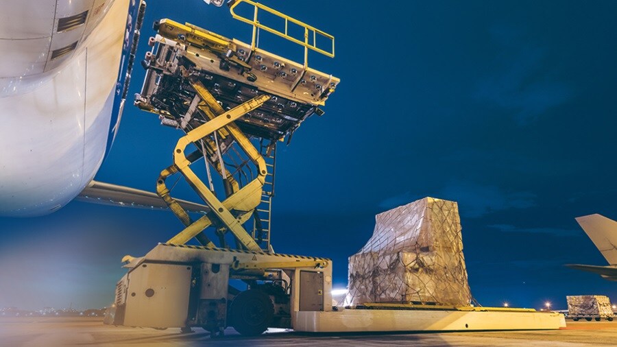 Yellow trolley being used to transfer cargo to an airplane