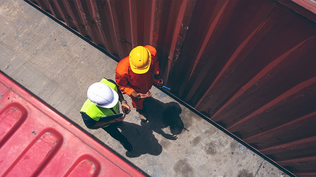Two man talking between containers