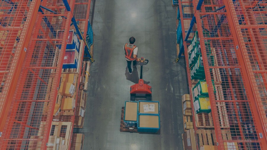 Male pulling a trolley with shipments in a warehouse