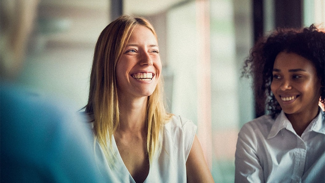 Two women working in supply chain industry smiling and discussing latest logistics trends.
