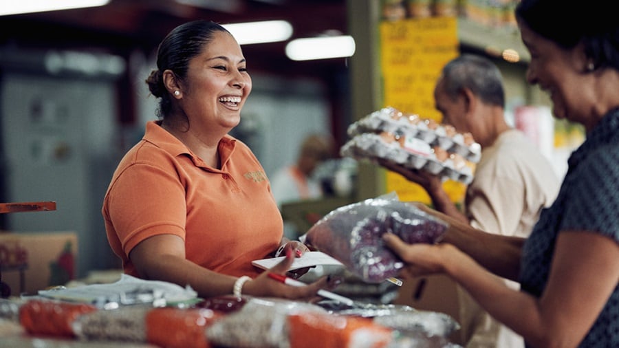 Person in an orange shirt is handing over a plastic-wrapped package