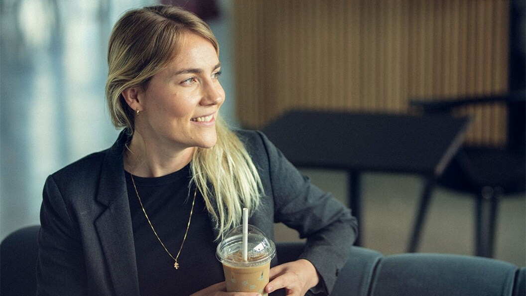 Woman sitting at an office with a cup of coffee.