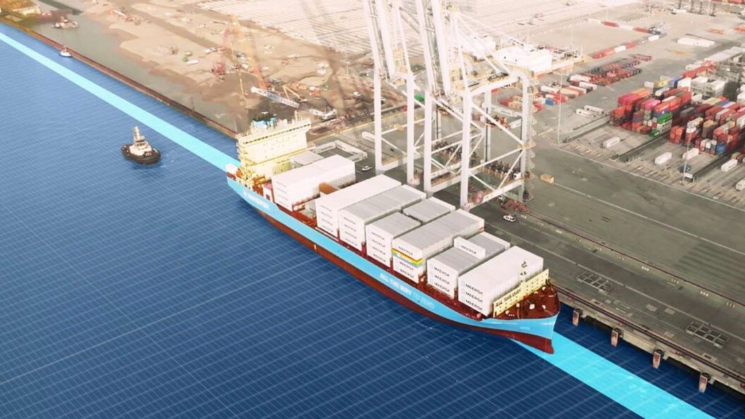 Cargo ship docked at port with containers being loaded by large cranes.