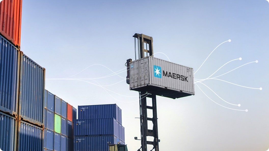 A container truck carrying a large shipping container on its flatbed, parked on a loading dock.