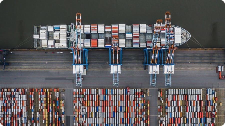 Aerial view of a large container ship surrounded by colorful cargo containers on the water.