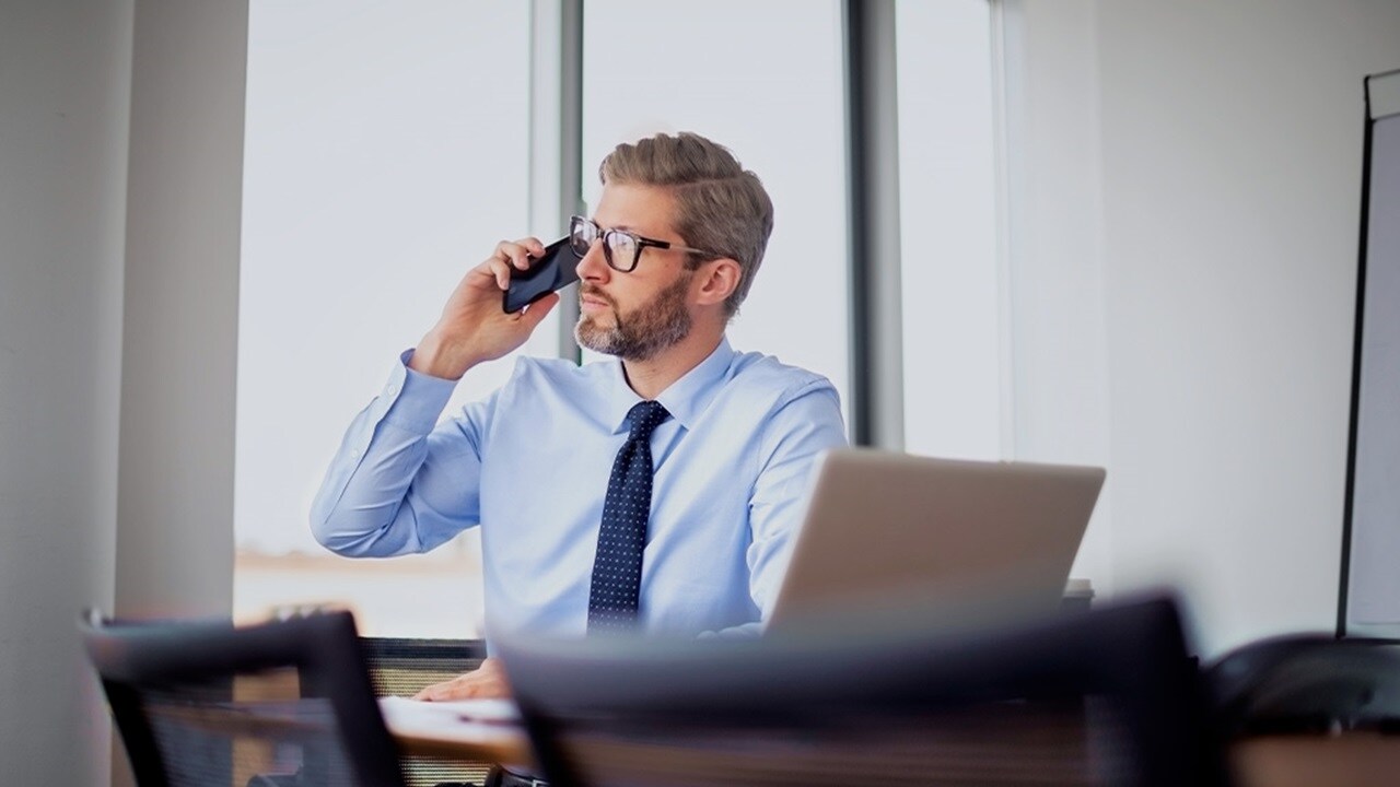 A man in a shirt and tie is engaged in a phone conversation.