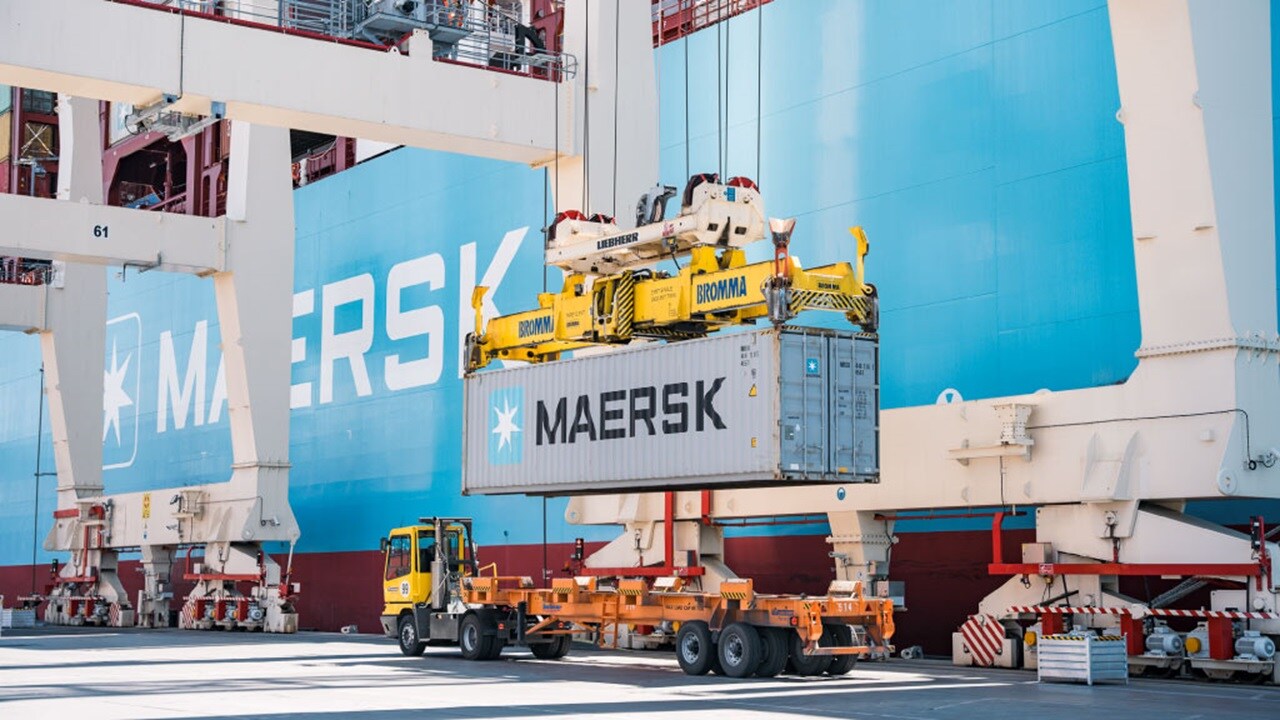 A crane lifts a large container at a construction site.