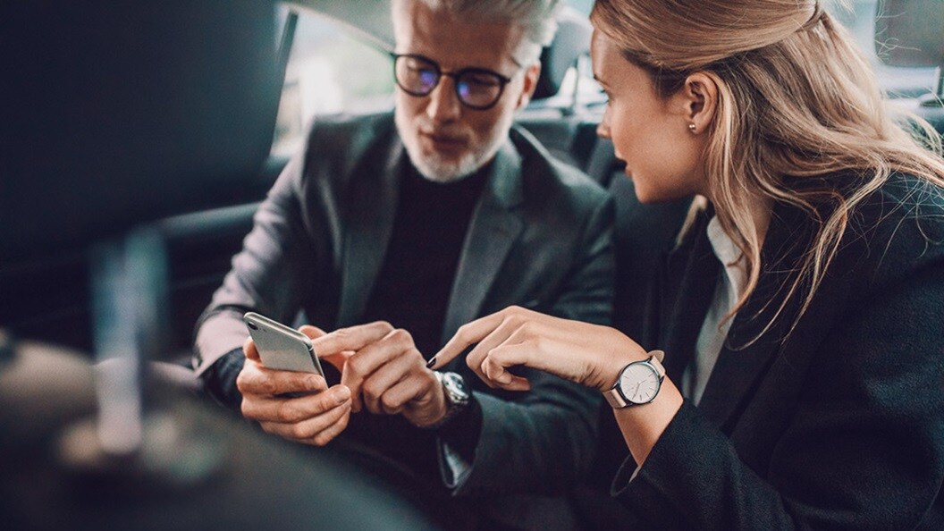 A man and a woman sitting in a car looking at a phone
