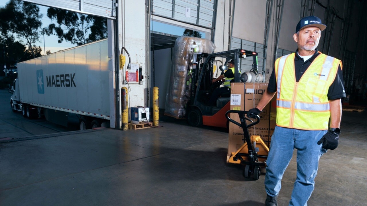 仓库工人驾驶叉车，将木托盘上的装运纸箱装上东升国际集装箱卡车。